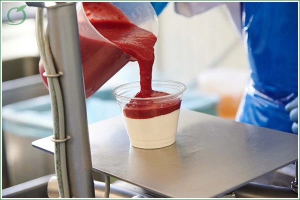 Bild zeigt, wie eine Fruchtsauce in einen Becher gefüllt wird.