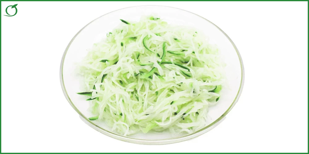 Bild zeigt den Kohlrabi-Gurkensalat, portioniert auf einem Glasteller auf weißem Grund