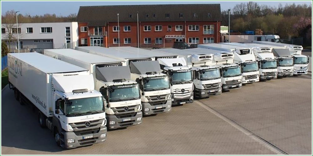 Bild zeigt zehn FRIKON-LKW, der Größe nach in einer Reihe nebeneinander aufgestellt vor den FRIKONI Firmengebäuden im Hintergrund