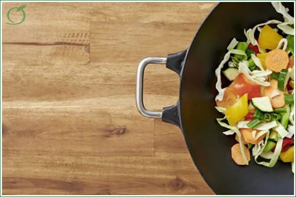 Das Bild zeigt eine an halbe Pfanne mit Wok-Gemüse auf einer Holtunterlage