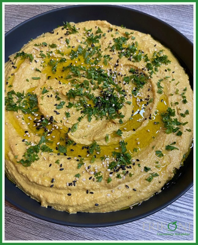 Bild zeigt eine Portion Kürbis Hummus mit Petersilie und Sesamsamen bestreut und mit Olivenöl betreufelt