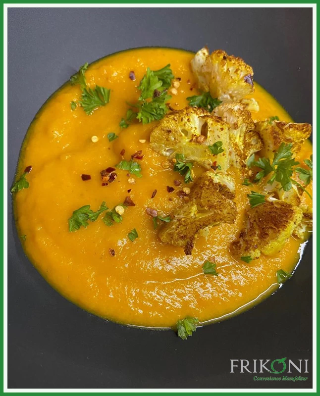 Bild zeigt die Suppe auf einem dunkelblauen Teller, garniert mit frischer Petersilie.