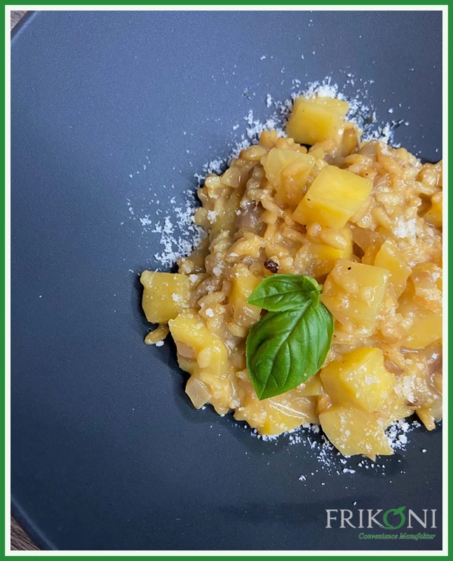 Bild zeigt das Risotto auf einem blauen Teller, garniert mit frischen Basilikum-Blättern.